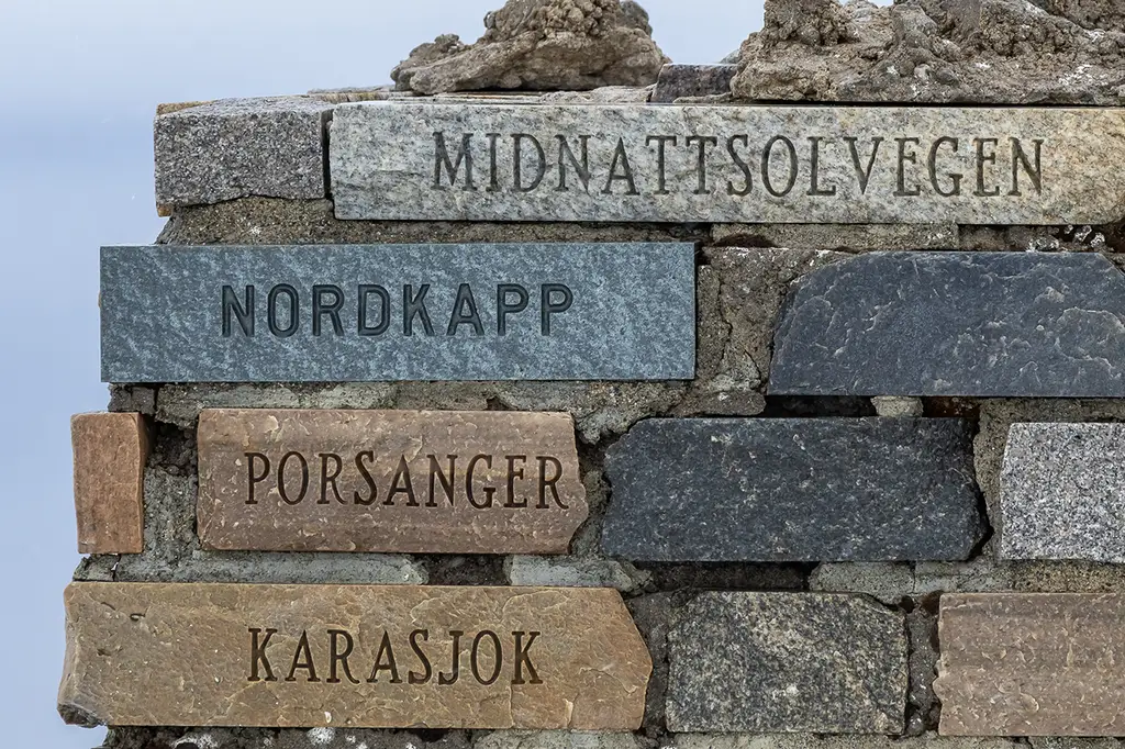 Signpost in northern Norway marking Midnattsolvegen, Nordkapp, and Porsanger, highlighting the route of the T33 motorcycle adventure.