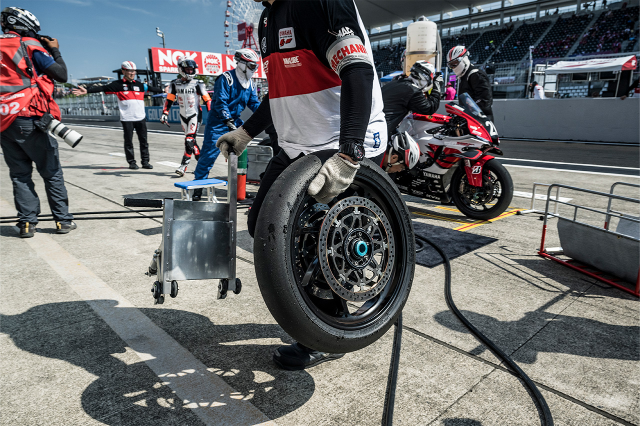 Mecánico sosteniendo una Bridgestone Neumático de motocicleta en boxes durante la Suzuka 8 Hours carrera.
