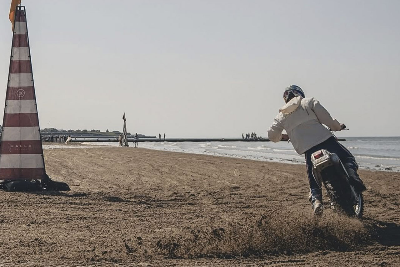 Hubert riding a motorcycle along the beach at a UK beach race