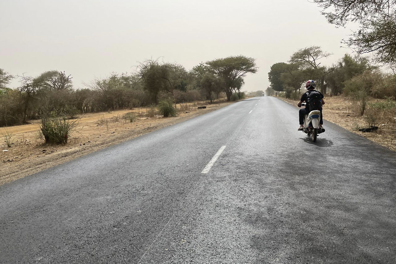 A rider on a small moped on a dusty road in Senegal