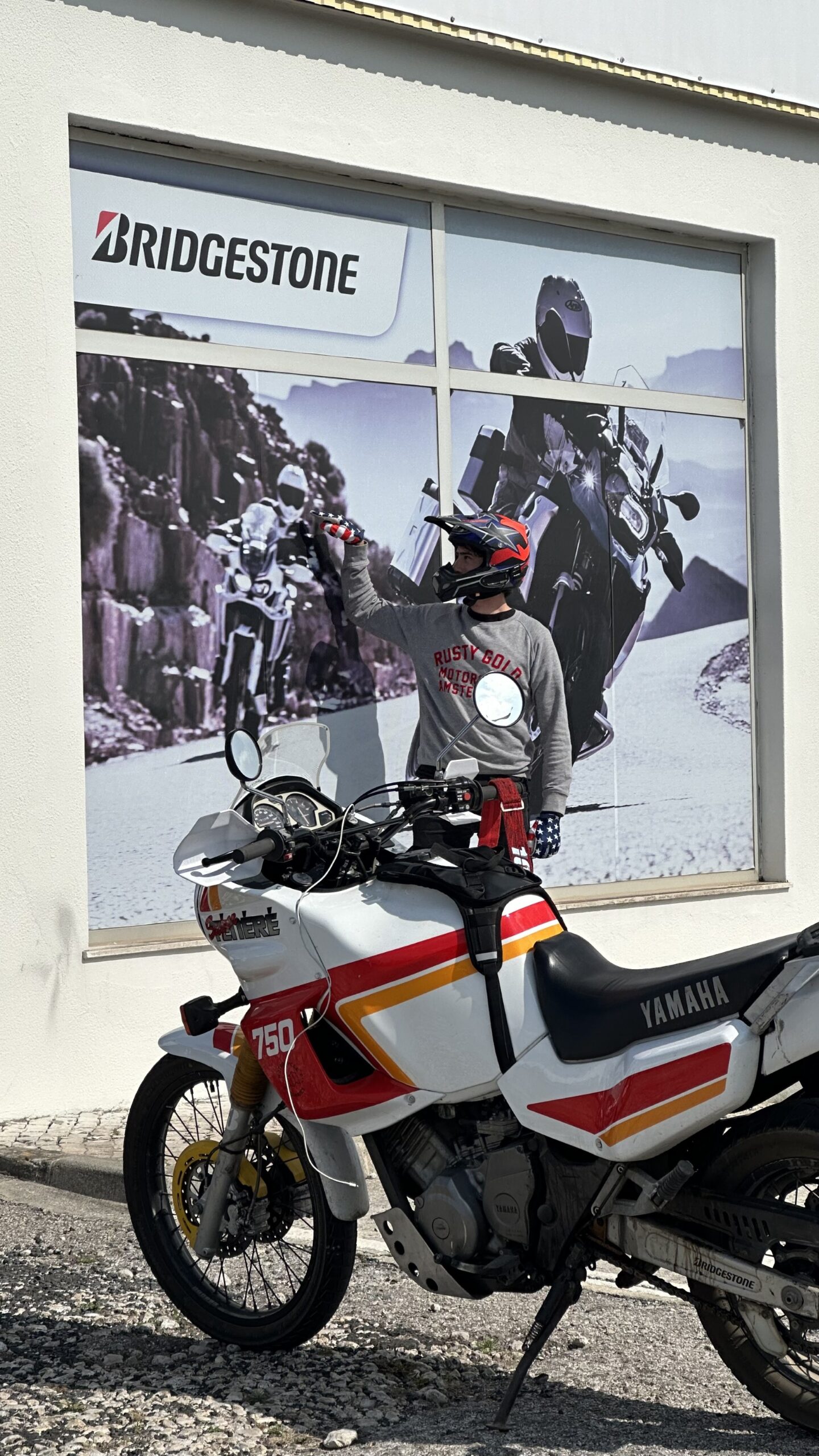 Hubert beside a vintage Yamaha Ténéré 750 in front of a Bridgestone mural in Portugal