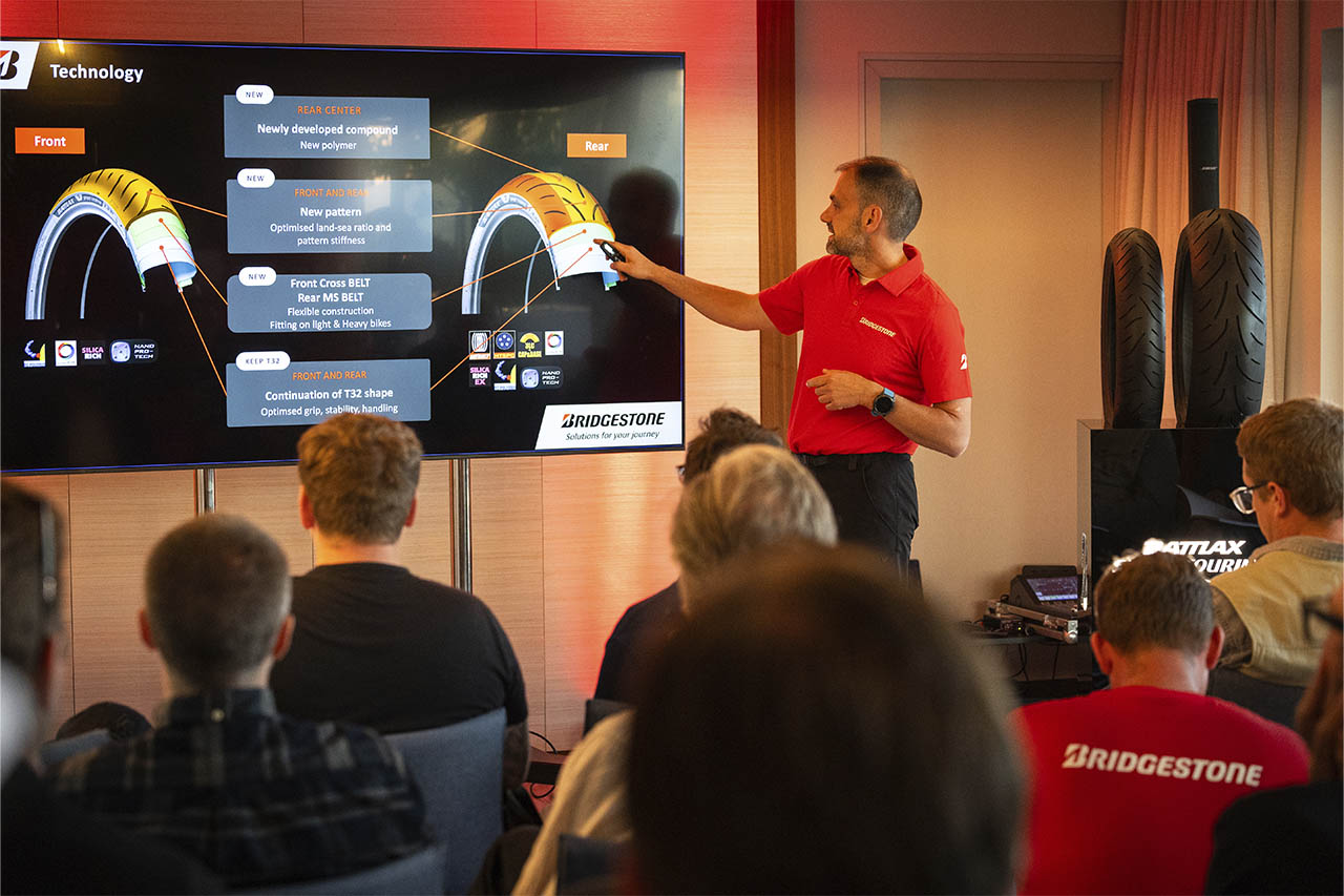 Dominique Plom presenting Battlax T33 tyre technology details to a seated group indoors.