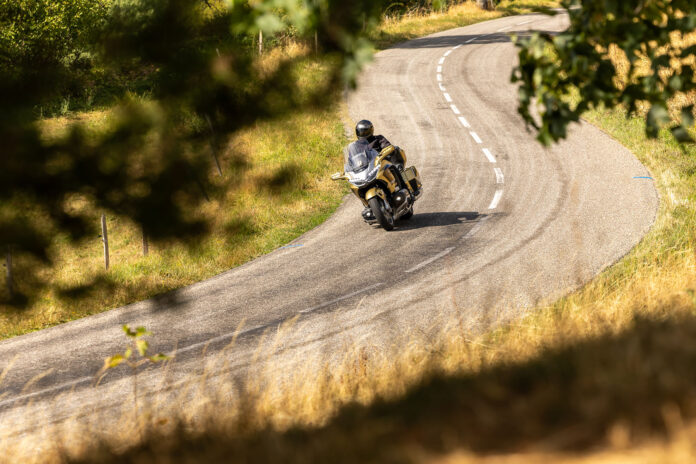 Honda GoldWing in gold 50th Anniversary colours leaning into a winding bend through the French countryside.