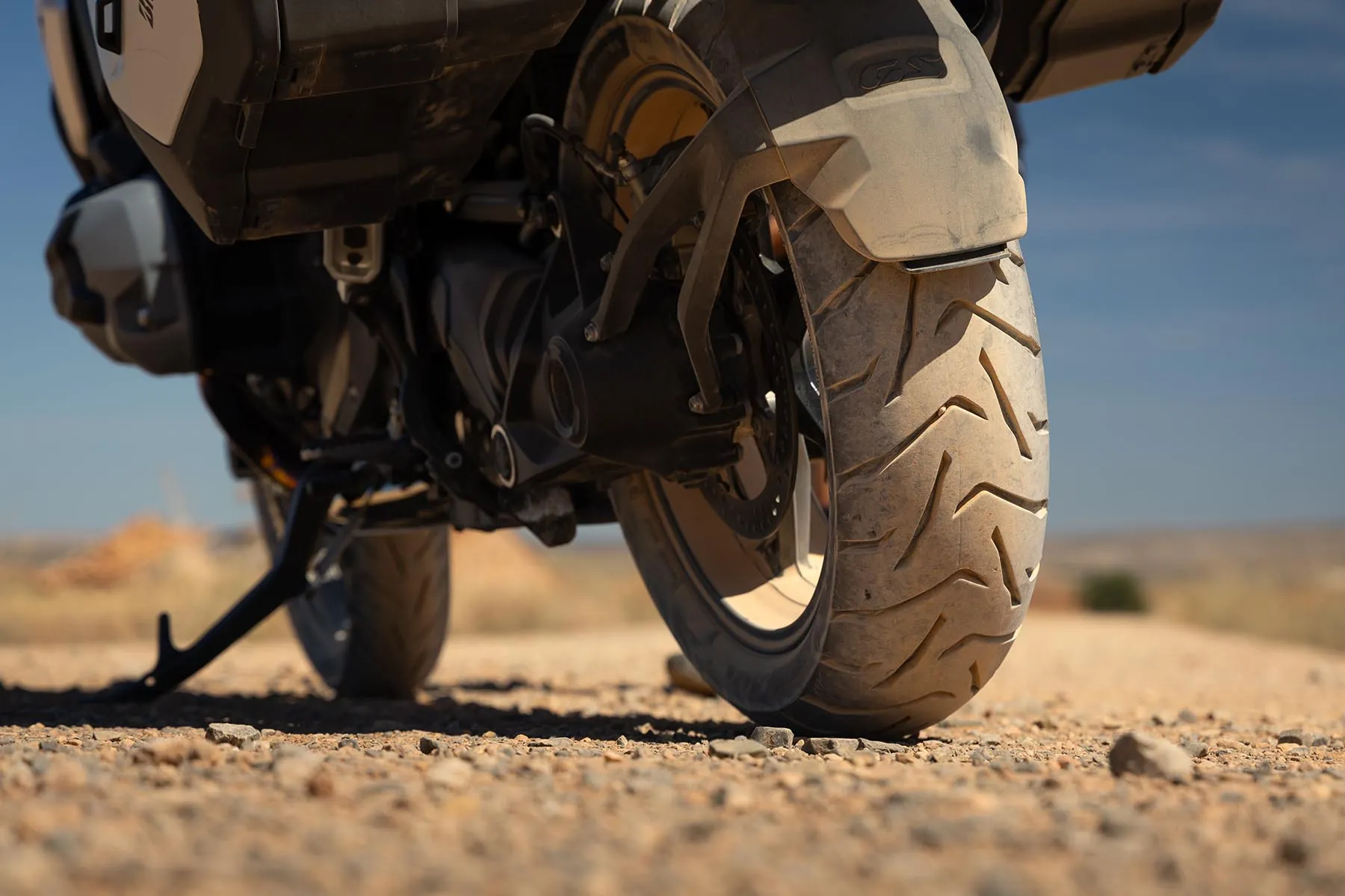 Low-angle close-up of the Bridgestone Battlax Adventure A42 rear tyre tread on a gravel road